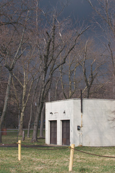 A white building, barren trees, and storm clouds in the background