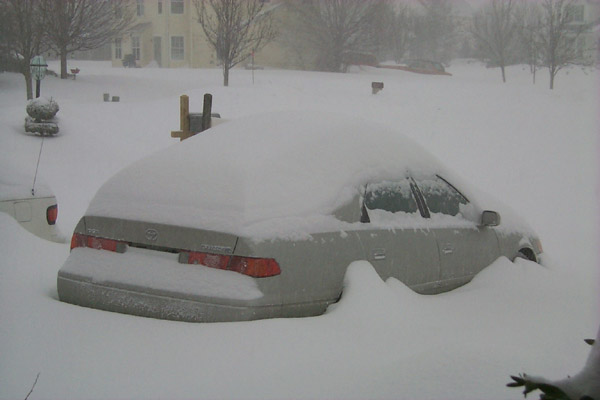 Snow drifting halfway up the door of my car, reaching the bumper
